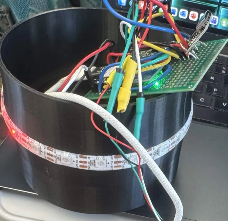 The SipSync enclosure opened up, showing the perfboard, microcontroller and wiring inside, with the LED strip lit red